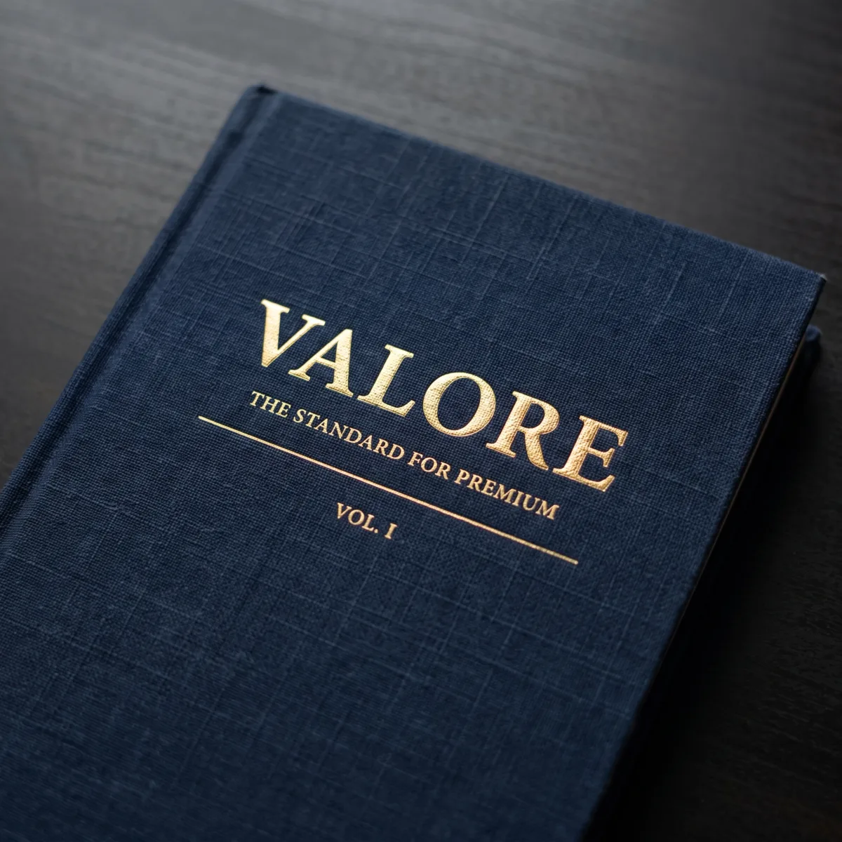 A navy linen hardcover book embossed in gold reading Valore, The Standard for Premium